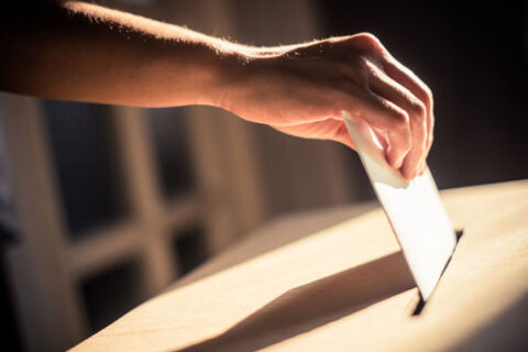 mano introduciendo un voto en una urna