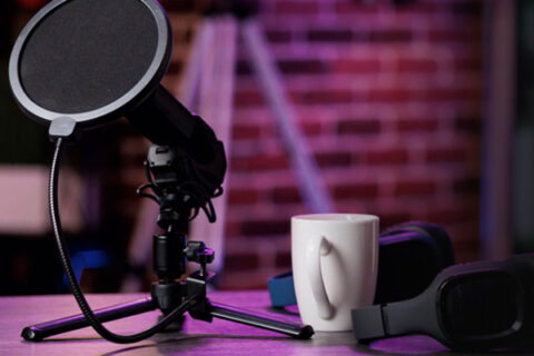 podcast mesa con microfono audifonos y una taza
